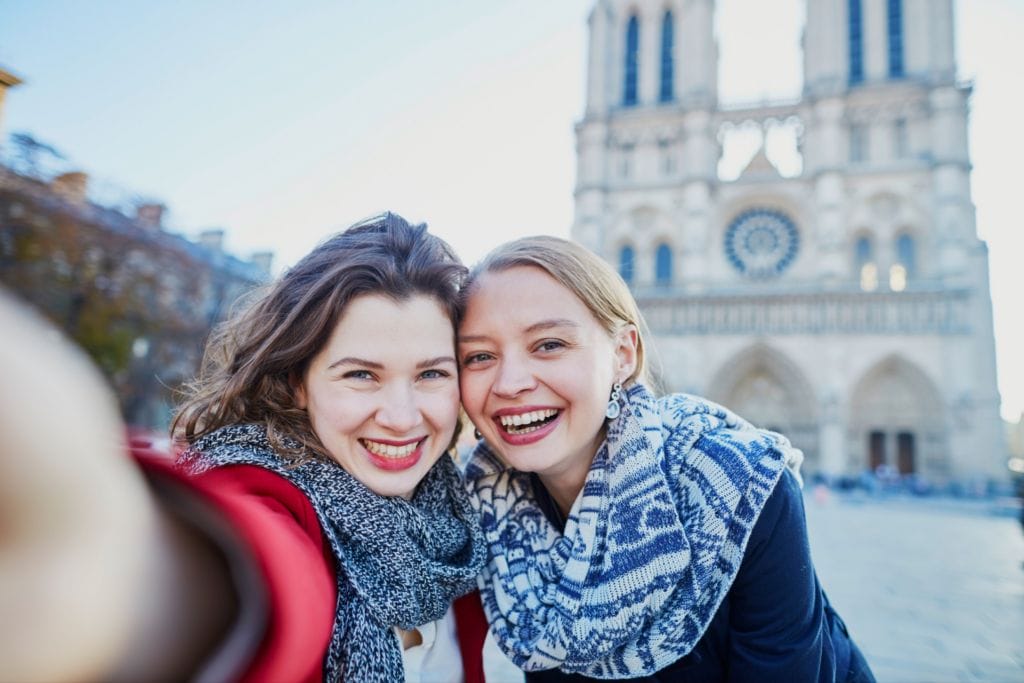 Dos mujeres radiantes disfrutando de su tiempo en Francia, con grandes sonrisas en sus rostros, ilustrando la felicidad y la satisfacción que se obtiene al aprender francés.